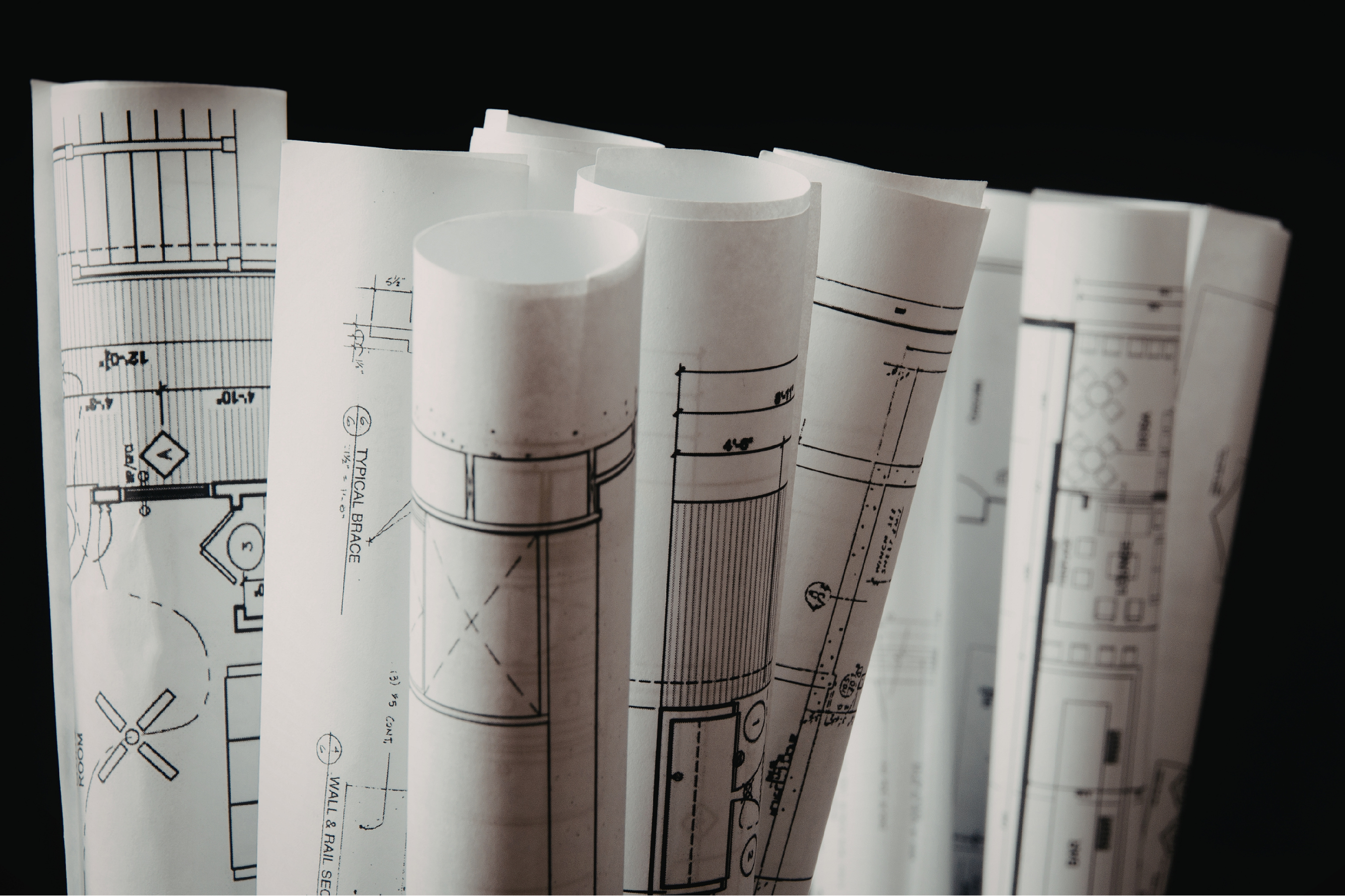 rolled up blueprint documents stacked upright against a black background