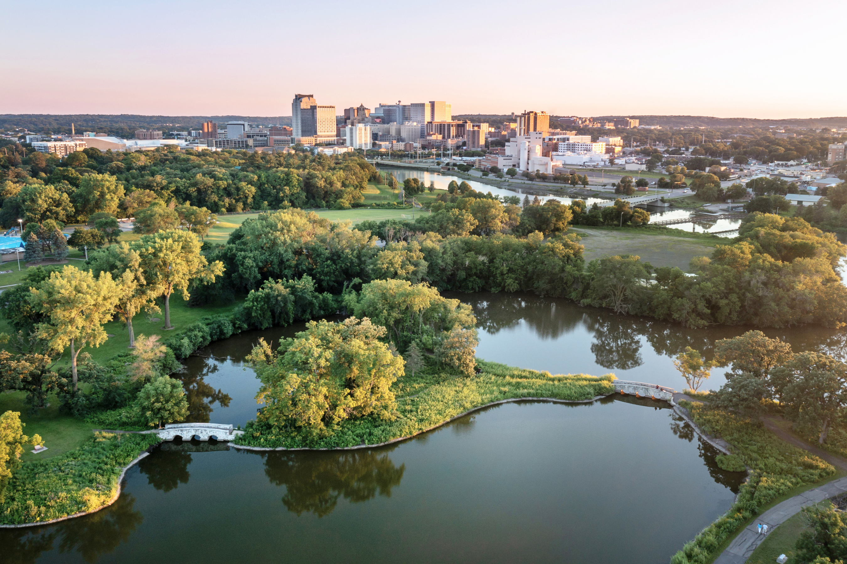 a calm lake in the foreground with the City of Rochester skyline in the background