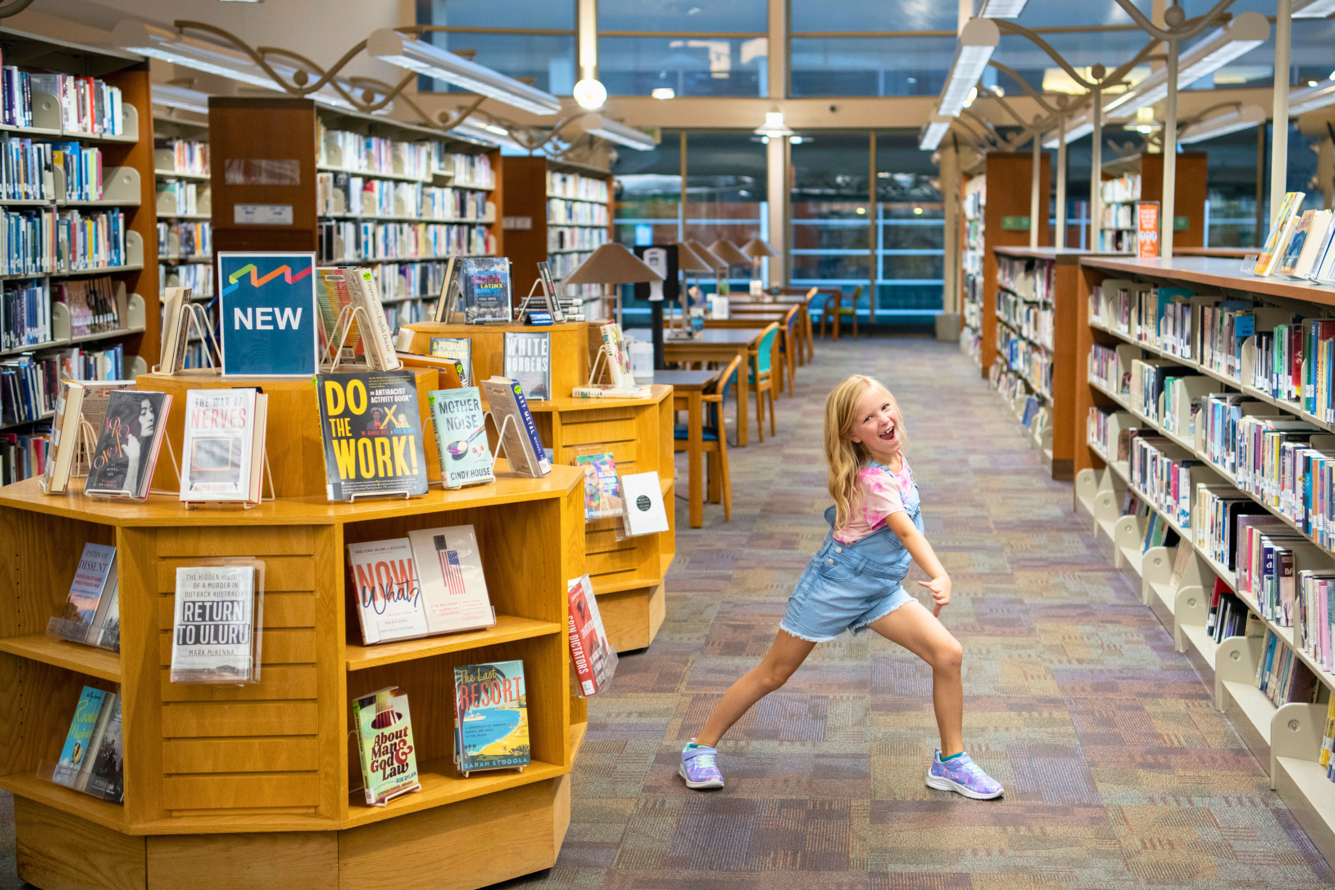 a young girl happily posing for the camera between stacks of books